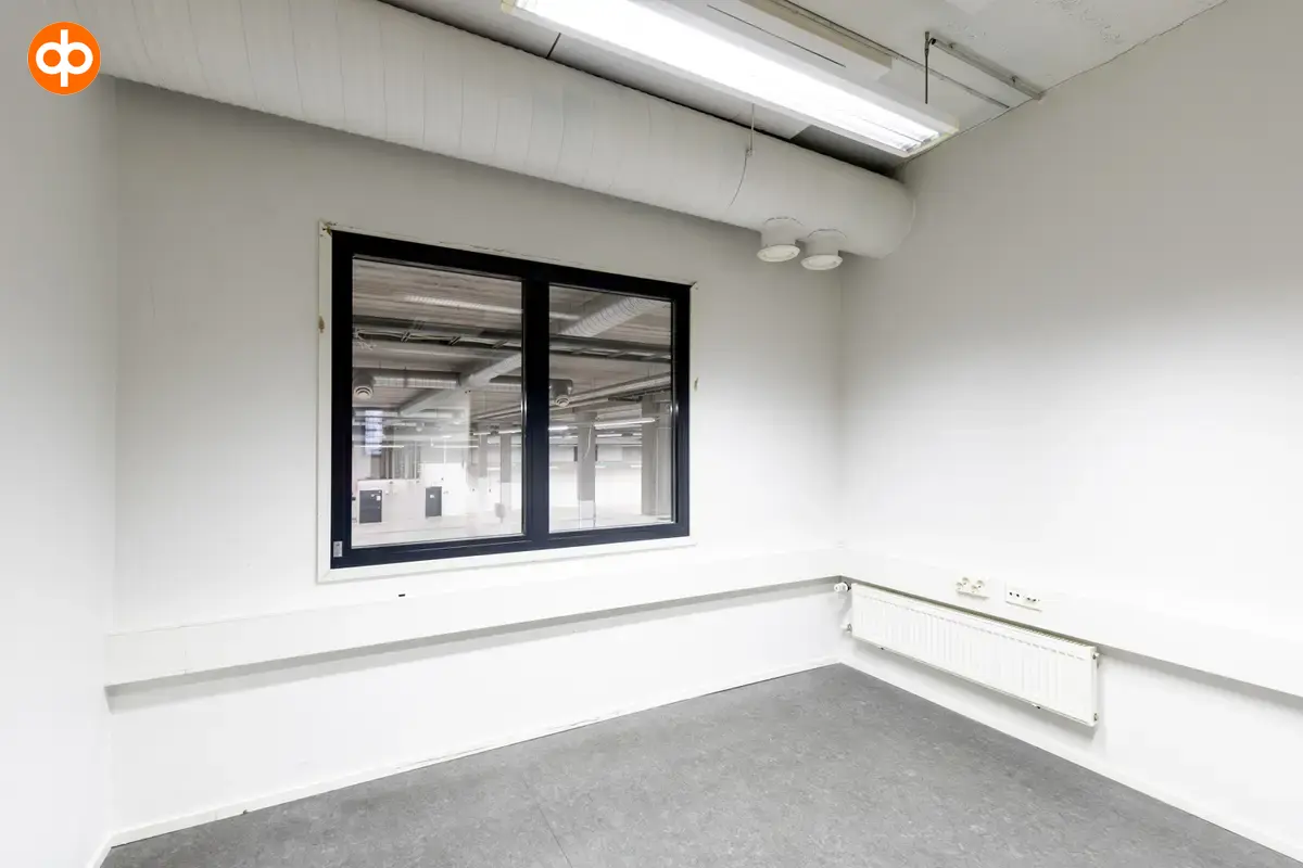 Interior view of the 3278 m2 office space on the 1st-2nd floor of Silvastintie 1, Vantaa. Office room with gray floors and white walls. Window on the back wall to the storage space on the ground floor