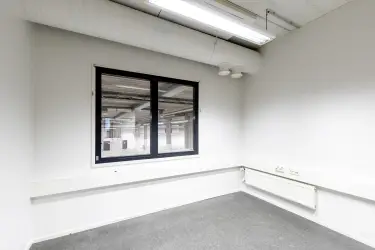 Interior view of the 3278 m2 office space on the 1st-2nd floor of Silvastintie 1, Vantaa. Office room with gray floors and white walls. Window on the back wall to the storage space on the ground floor