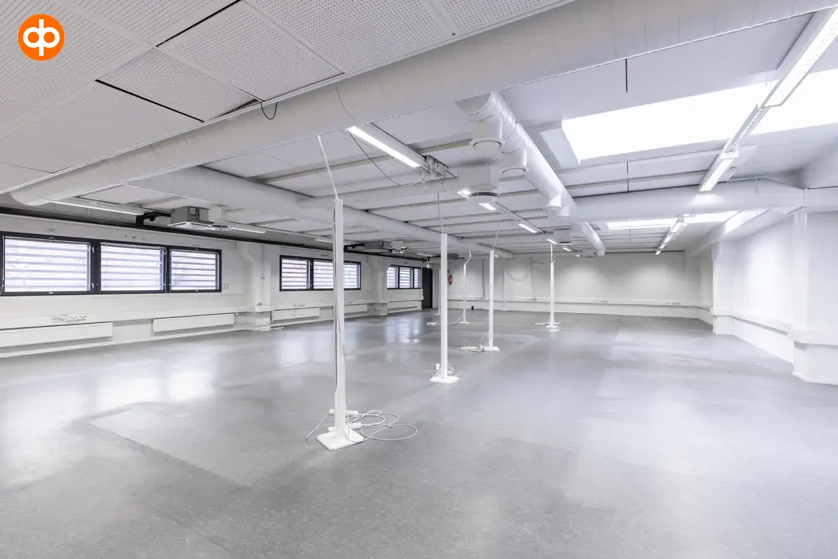 Interior view of the office space on the 2nd floor at Silvastintie 1, Vantaa. Empty open-plan office, the floors are light grey and the walls are white, with windows on the left wall.