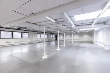 Interior view of the office space on the 2nd floor at Silvastintie 1, Vantaa. Empty open-plan office, the floors are light grey and the walls are white, with windows on the left wall.