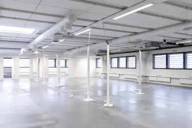 Interior view of the office space on the 2nd floor at Silvastintie 1, Vantaa. Empty open-plan office space with light surfaces, windows on the right wall, two separate office rooms behind open space.