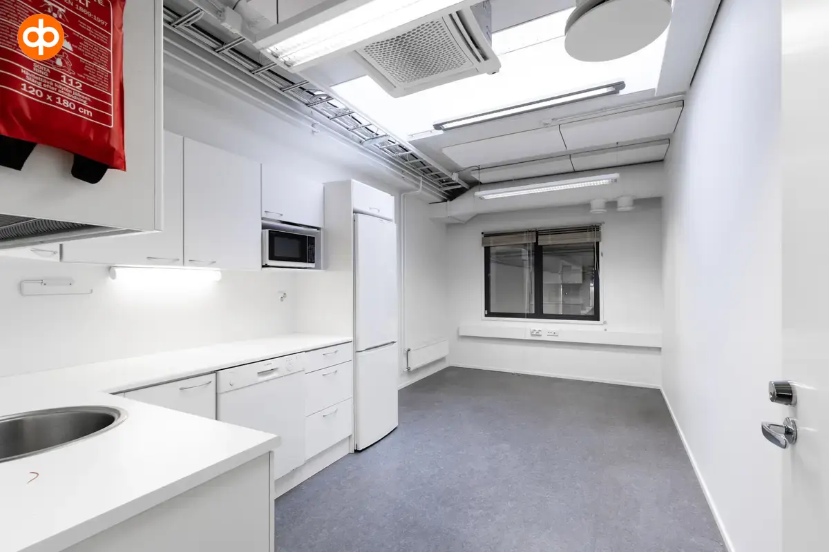 Interior view of the office space on the 2nd floor at Silvastintie 1, Vantaa. A room with a light-colored kitchen in the left corner. The room is otherwise empty, with a window on the back wall .