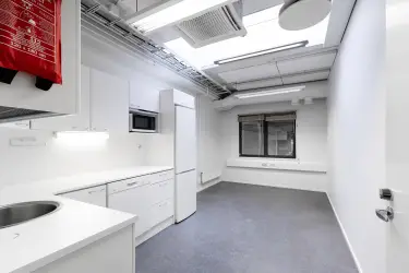 Interior view of the office space on the 2nd floor at Silvastintie 1, Vantaa. A room with a light-colored kitchen in the left corner. The room is otherwise empty, with a window on the back wall .