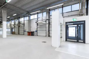Interior view of the office space on the 1st floor, Silvastintie 1, Vantaa. On the left side, a glass door to the outside. Next to the door, several lifting doors side by side.