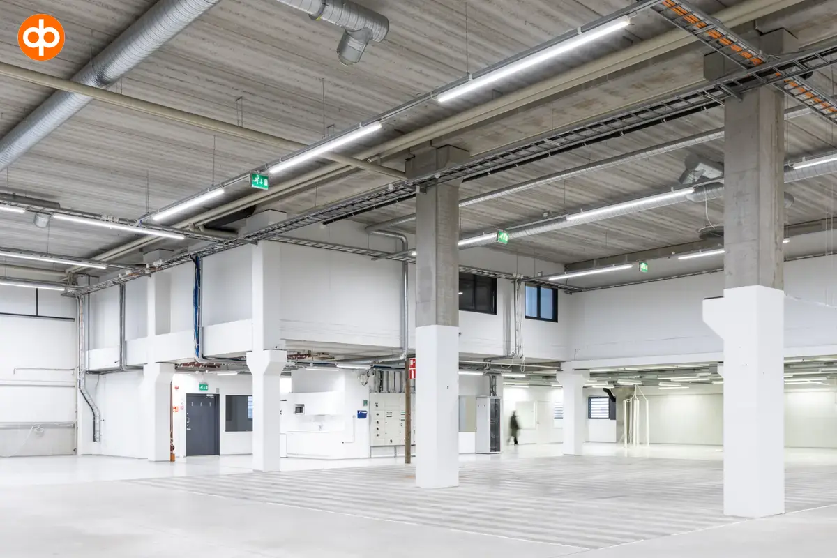 Interior view of the 3278 m2 office space at Silvastintie 1, Vantaa. Empty Warehouse space with light surfaces. Kitchen at the back of the space.