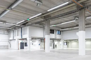 Interior view of the 3278 m2 office space at Silvastintie 1, Vantaa. Empty Warehouse space with light surfaces. Kitchen at the back of the space.