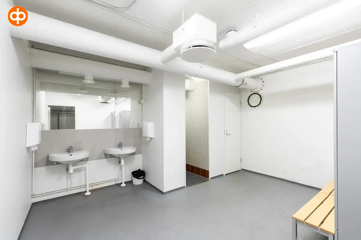 I am giving an interior photo of the Silvastintie 1 business premises. Toilet area with light surfaces, two hand basins side by side on the back wall, a door next to the basins to the adjacent toilet.