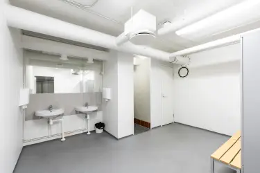 I am giving an interior photo of the Silvastintie 1 business premises. Toilet area with light surfaces, two hand basins side by side on the back wall, a door next to the basins to the adjacent toilet.