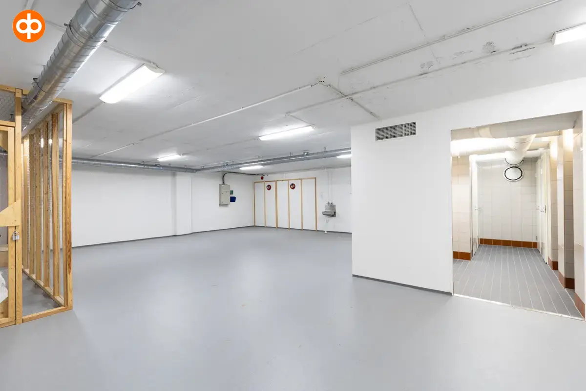 Interior view of the Vantaa Silvastintie 1 office building. Social area with gray floors and light walls, shower facilities on the right, empty open space on the right.