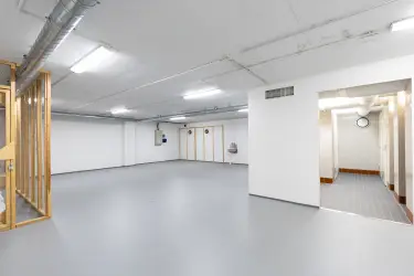 Interior view of the Vantaa Silvastintie 1 office building. Social area with gray floors and light walls, shower facilities on the right, empty open space on the right.