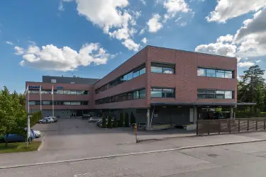 Martinkyläntie 17, toimitilakiinteistön ulkokuva. Kolmekerroksinen rakennus risteyksessä. Rakennus on harmaa ja tiilenoranssi. 