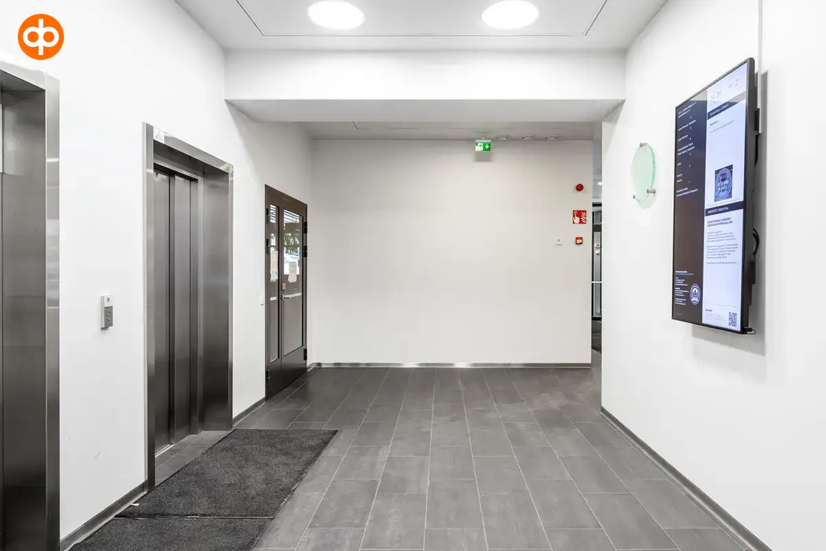 Toimitilakiinteistö Lönnrotinkatu 11:ta hissiaula. Seinällä sähköinen infotaulu.