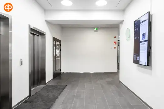 Toimitilakiinteistö Lönnrotinkatu 11:ta hissiaula. Seinällä sähköinen infotaulu.
