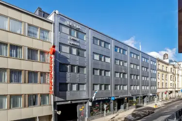 Kiinteistö Lönnrotinkadulla, jonka katutasossa liiketiloja. Rakennuksen edessä kulkee jalkakäytävä sekä autotie.