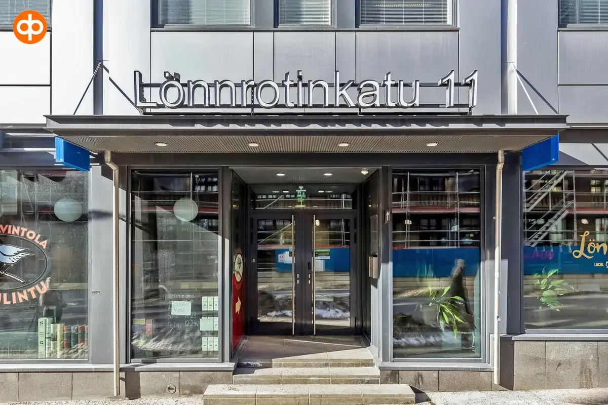 Lönnrotinkatu 11:ta sisäänkäynti rakennuksen ulkopuolelta kuvattuna. Suuret ikkunat ovien molemmin puolin.