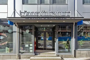 Lönnrotinkatu 11:ta sisäänkäynti rakennuksen ulkopuolelta kuvattuna. Suuret ikkunat ovien molemmin puolin.